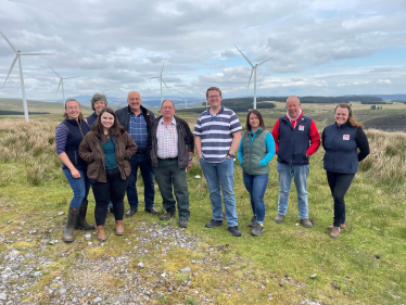 Joel James MS with FUW and Jones Family on hill farm with wind turbines in background